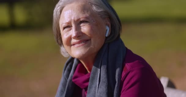 Senior kvinna lyssnar på musik på hörlurar vilar efter träning — Stockvideo