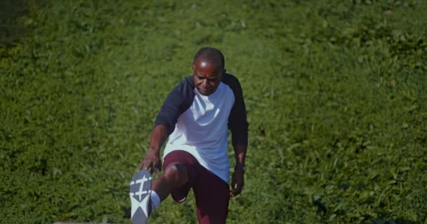 Älterer afrikanisch-amerikanischer Mann streckt Bein im Freien — Stockvideo