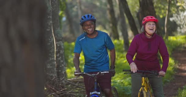 Senior friends ridding bicycles with helmets on forest — Stock Video