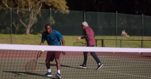 Kaksi vanhempaa miestä pelaa tennistä kentällä — kuvapankkivideo