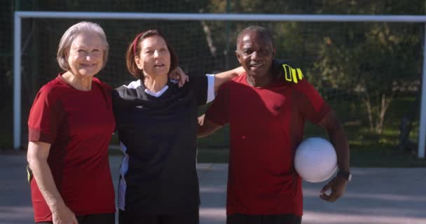 Gruppo di anziani su uniforme di calcio abbracciando palla holding — Video Stock