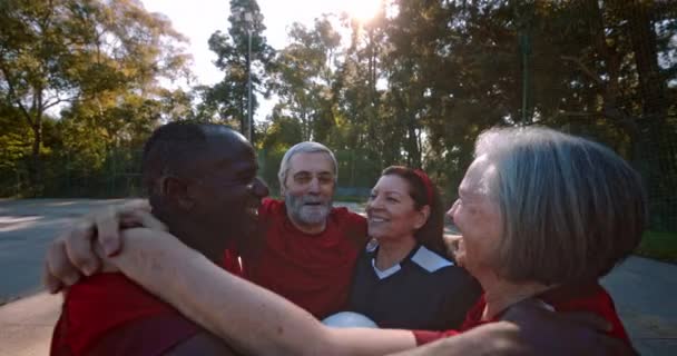 Група літніх людей в колі обіймає святкування перемоги у футбольних матчах — стокове відео