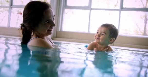 Мати грає з дитиною в критому басейні — стокове відео