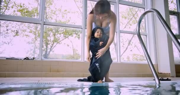Moeder wikkeling handdoek rond baby drogen aan overdekt zwembad kant — Stockvideo