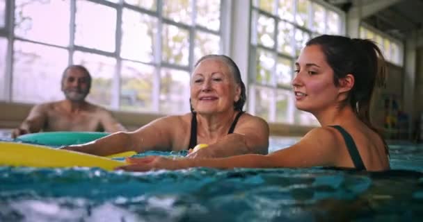 Entraîneur instruire femme aînée exerçant avec piscine nouilles classe d'aérobic — Video