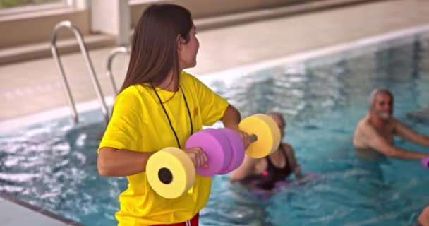 Entrenador instruyendo clases de aeróbic acuático para el grupo de personas mayores — Vídeos de Stock