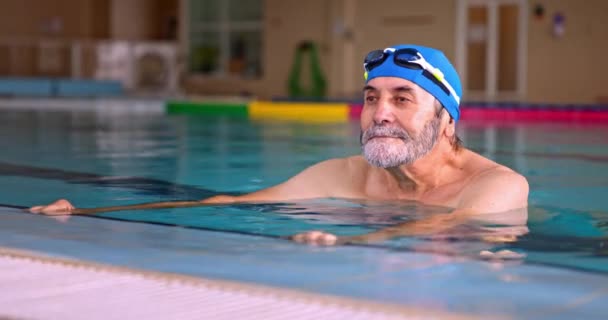 Hombre mayor sosteniendo piscina execising en piscina cubierta — Vídeos de Stock