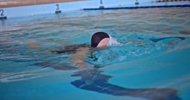 Mujer mayor nadando en piscina cubierta — Vídeo de stock