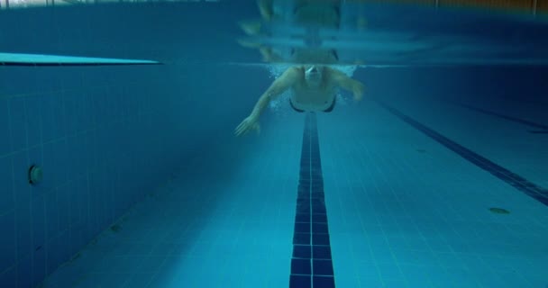 Ампутированный адаптивный спортсмен-бабочка плавает в закрытом бассейне под водой — стоковое видео