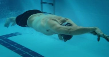 Uyarlanabilir ampüte sporcu kapalı havuzda suyun altında yüzüyor.