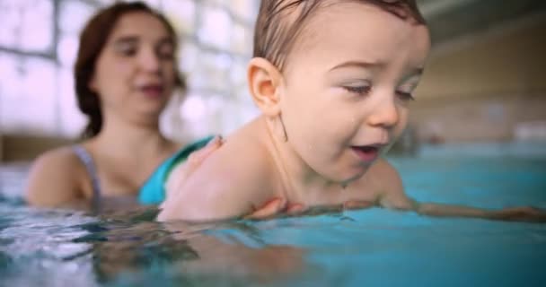 Mère enseignant bébé fils à nager dans la piscine intérieure — Video