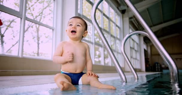 Mignon bébé assis sur le bord latéral de la piscine intérieure — Video