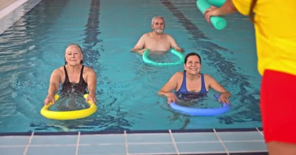 Coach giving pool noodle senior aerobics class in pool Royalty Free Stock Video