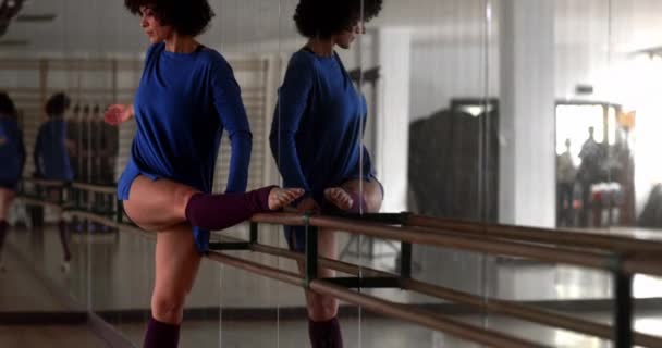 African-american woman stretching body on ballet barre in dance studio Stock Video