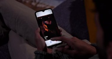 Evdeki cep telefonunda flört uygulaması kullanan bir adam