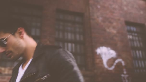 Young man wearing sunglasses walking in urban area — Stock Video