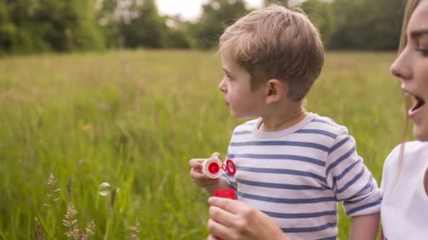 Мать и сын веселятся с пузырьками в парке — стоковое видео
