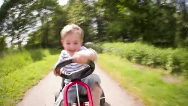 Liten pojke ha kul körning en trampbil — Stockvideo