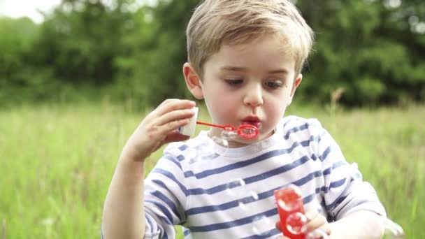 El niño está extasiado por soplar burbujas. — Vídeos de Stock