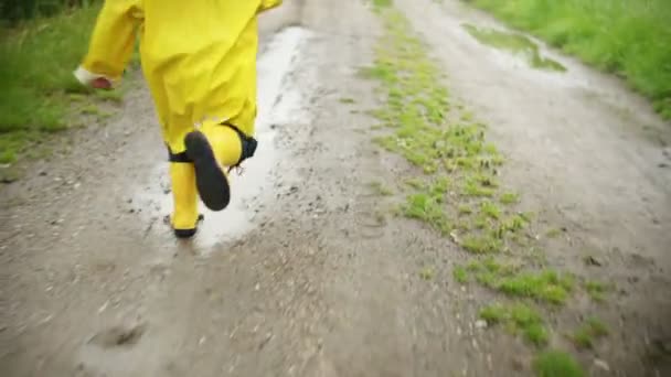 Мальчик бежит на улицу после дождя — стоковое видео