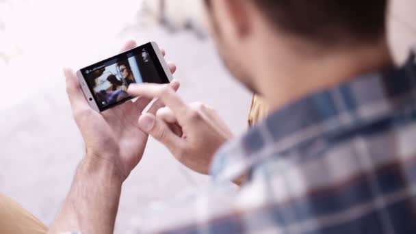 Man gebruikt smartphone om te kijken naar foto 's — Stockvideo