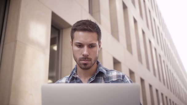Человек, сидящий снаружи и работающий с ноутбуком — стоковое видео