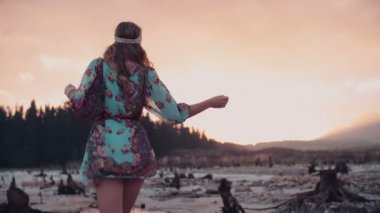 Boho kız gün batımında suda ayakta