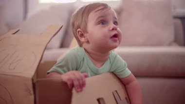 Bir karton kutunun içinde oynayan erkek bebek
