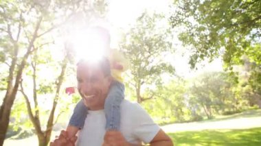 Küçük kızı omuzlarında taşıyan baba