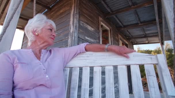 Mujer mayor relajándose en el porche delantero — Vídeo de stock