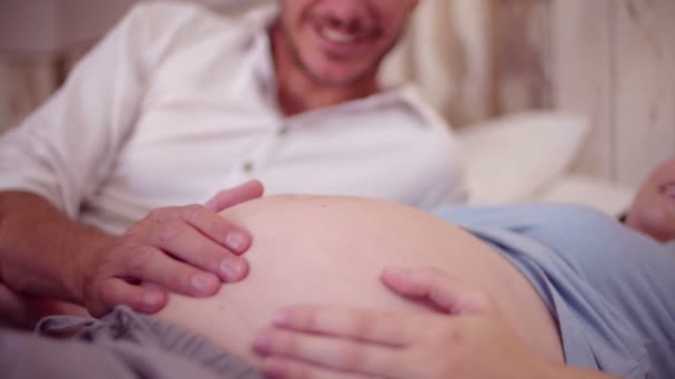 Чоловік торкається своїх дружин вагітного живота — стокове відео