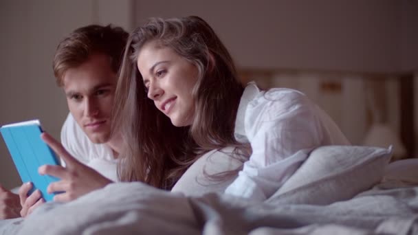 Ζευγάρι στο κρεβάτι που μοιράζονται μια ψηφιακή δισκίο — Αρχείο Βίντεο