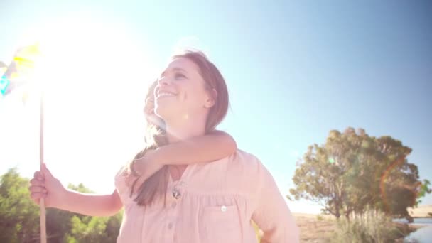 Madre e hija con un molino de viento colorido — Vídeos de Stock