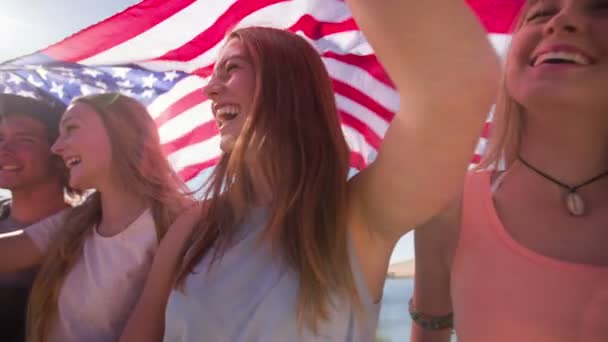 Adolescentes amigos segurando uma bandeira americana — Vídeo de Stock