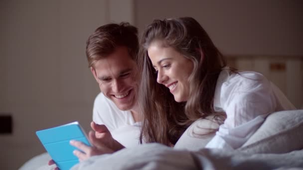 Pareja en la cama compartiendo una tableta digital — Vídeos de Stock