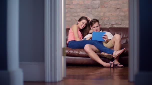 Couple using a digital tablet on a sofa — Stock Video