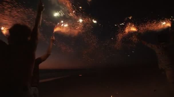 Amigos correndo em uma praia com fogos de artifício — Vídeo de Stock