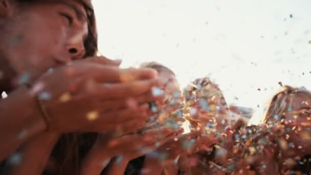 Teens blowing colorful confetti outdoors Stock Footage