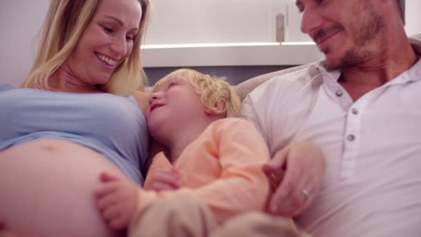 Мальчик на диване с папой и беременной мамой — стоковое видео
