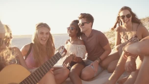 Amici ad una festa sulla spiaggia al tramonto con una chitarra — Video Stock