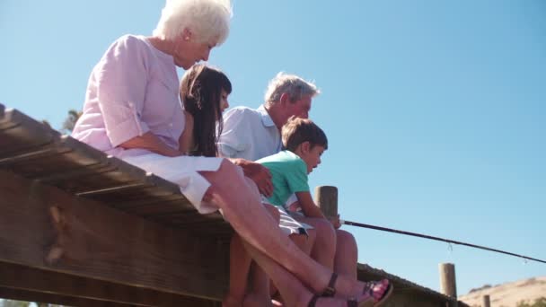 Grands-parents assis avec des petits-enfants sur une jetée — Video