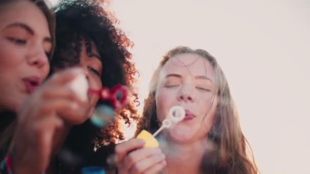 Kız arkadaşlar kabarcıklar günbatımında üfleme — Stok video