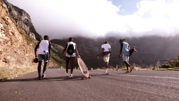 Друзья-фигуристы идут по горной дороге — стоковое видео