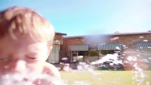 Smiling little boy spraying water — Stock Video