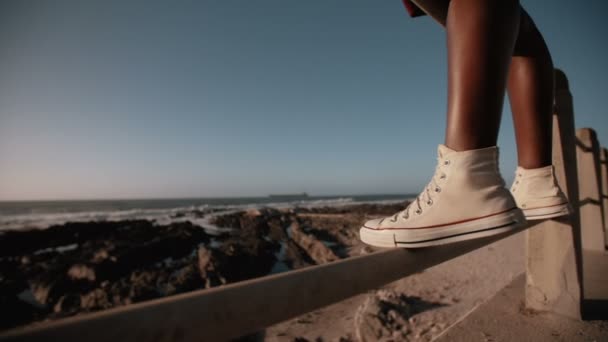 Девушка в кроссовках стоит на берегу моря — стоковое видео