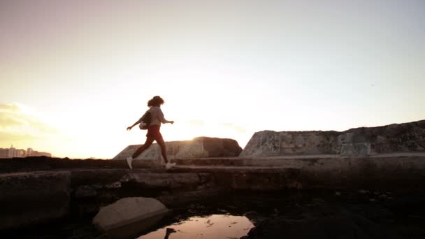 Mädchen springt über Felspool — Stockvideo