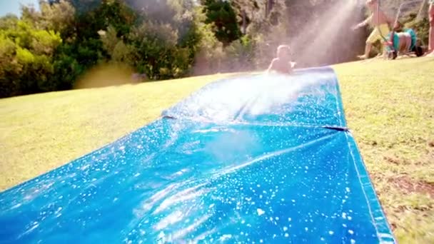 Boy sliding down slippery water slide — Stock Video