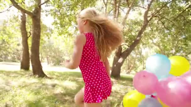 Girl running with balloons in a park — Stock Video
