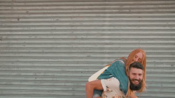 Girl laughing while hipster boyfriend piggyback — Stock Video