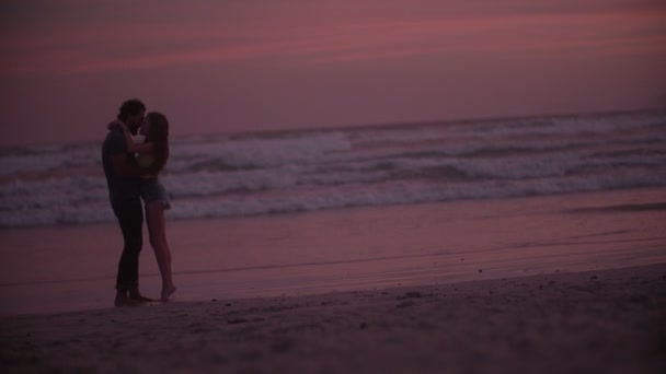 Любляча пара на пляжі на заході сонця — стокове відео